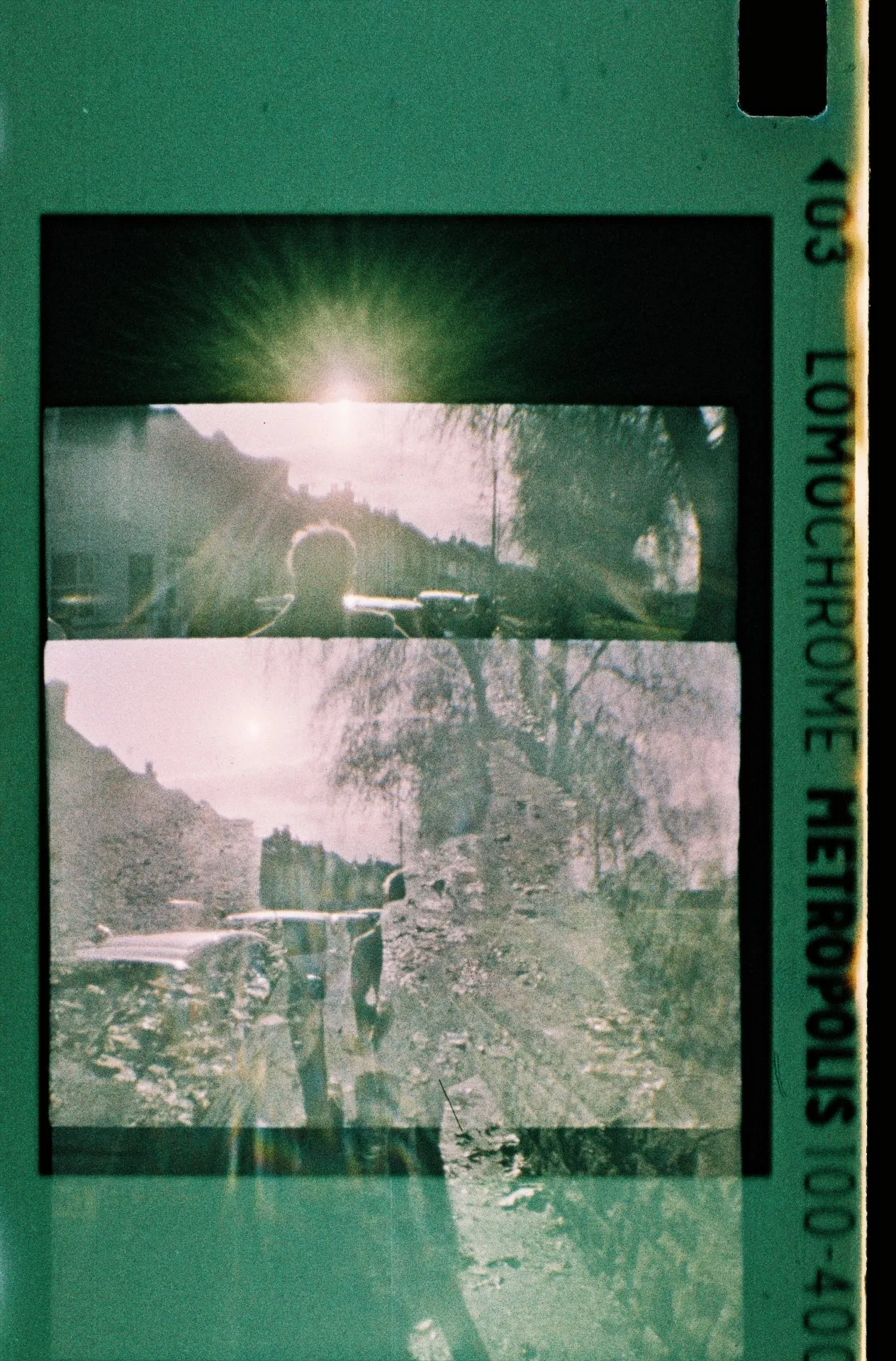Another double exposure. This one is of a street and somebody walking along a path. The roughness of the path overlayed over the street view gives a kind of post-war rubble vibe, though in reality it was a nice autumn day. Some of the film edge is in view, showing the text "Lomochrome Metropolis 100-400"