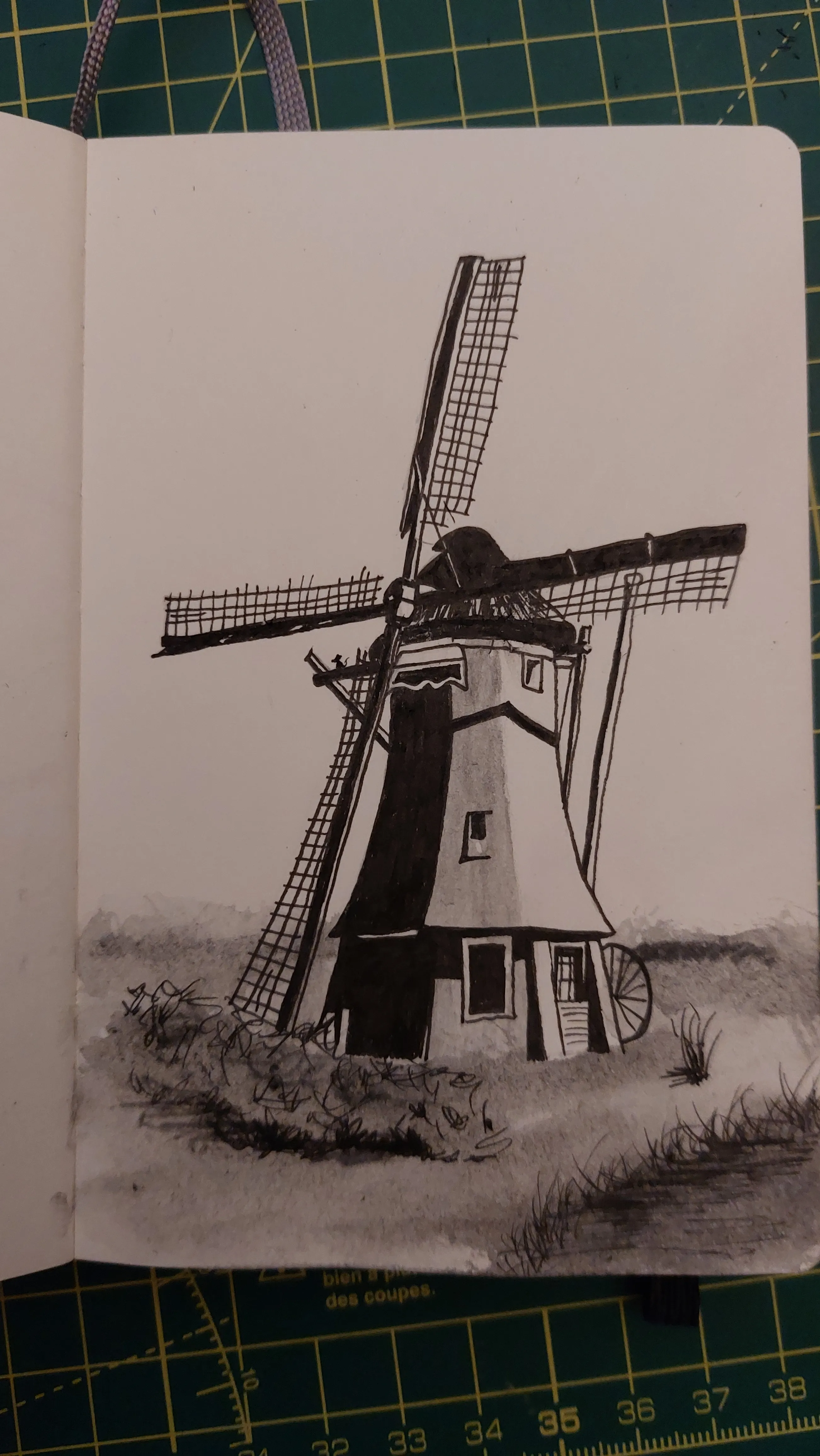 A sketch of a windmill. Harsh black and white with some grey watercolour shading. There is a small mouse hiding in the image.