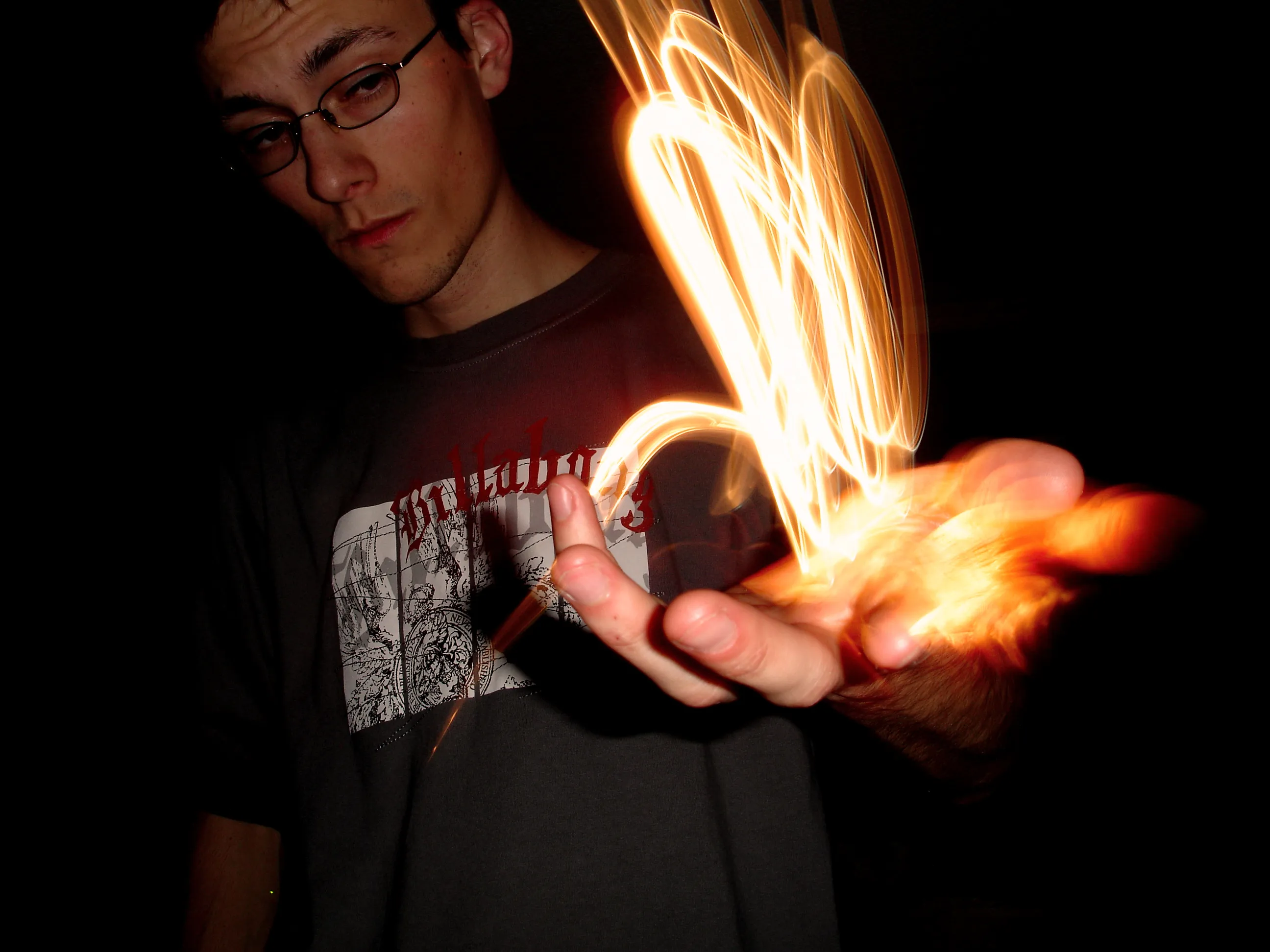 A photo of a man with an outstretched hand. In the hand is a pile of light, like he's profferring a flame.